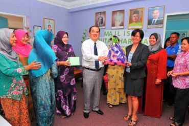 Winning smile: Sabah Youth and Sports Minister Datuk Peter Pang who was the guest-of-honour, presenting a lucky draw prize to a Kosan staff during the Hari Raya open house recently.
